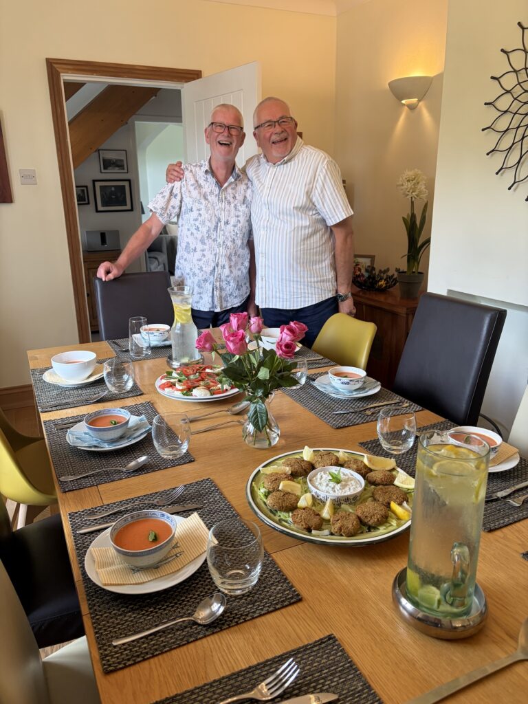 Two men about to sit at a dining table