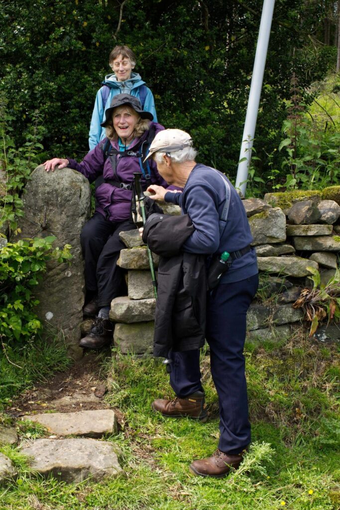 3 of the Hiking Group members navigating a stile