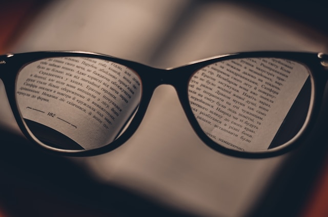 text in a book viewed through a pair of reading glasses